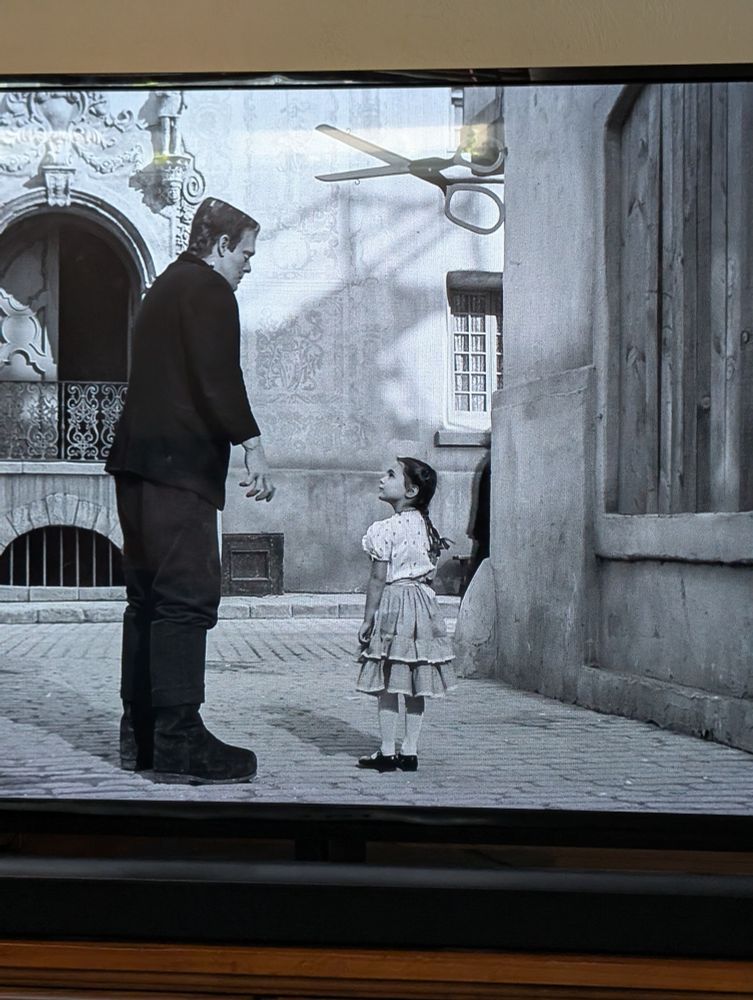Frankenstein looks down at a little girl with pigtails