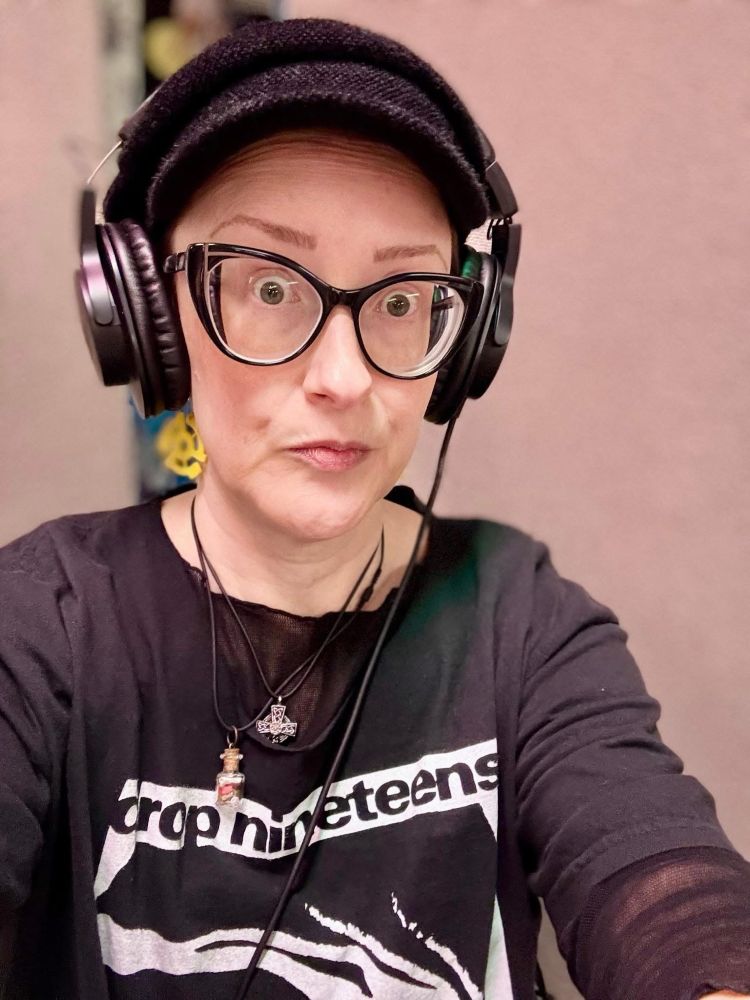Photo of user wearing giant headphones and a Drop Nineteens shirt. She is looking quizzical and yet not amused.