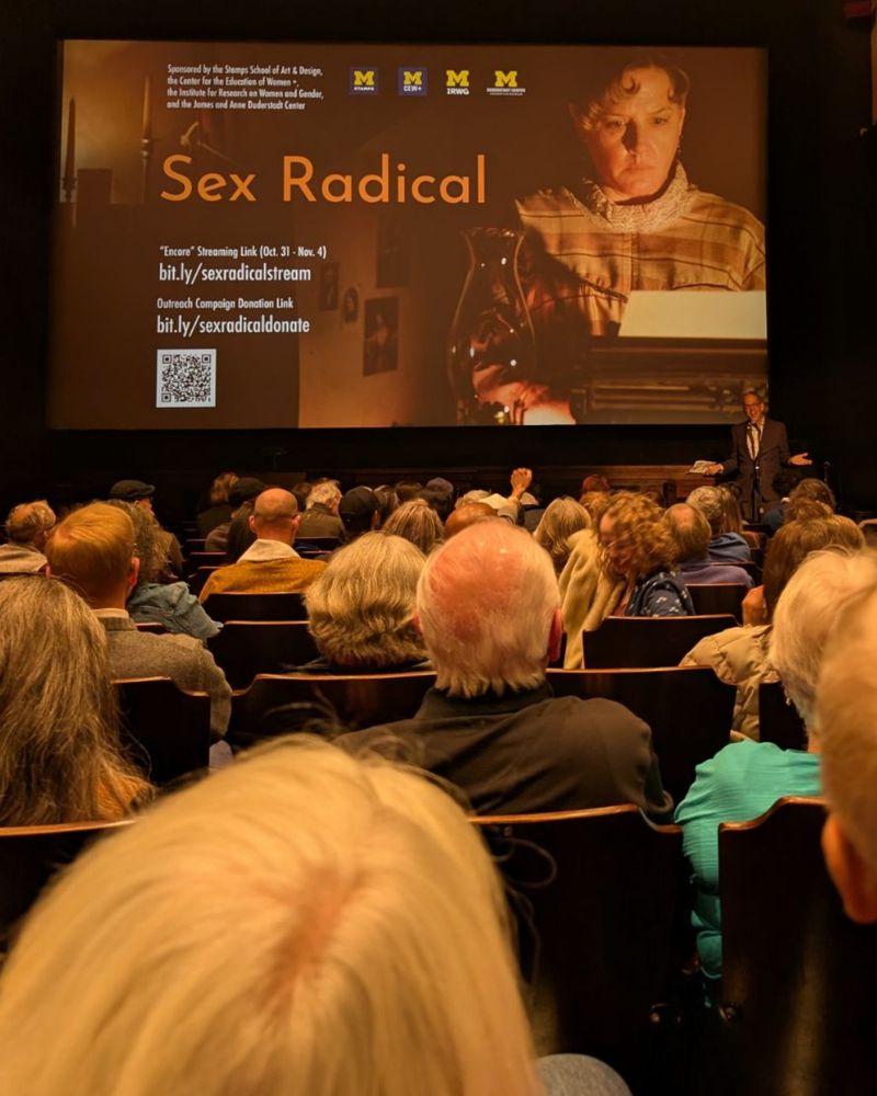 Theater with promotional screen for the film “Sex Radical” showing, with filmmaker Andy Kirshner speaking to the crowd.