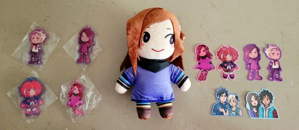 A picture of a plushie of Akane Kurashiki from Zero Escape surrounded by various stickers and charms featuring Santa, Clover, Junpei, Phi and Sigma.