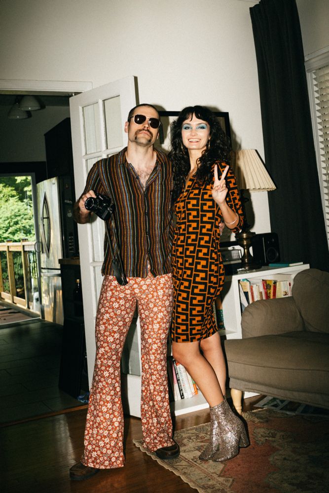 My wife and I dressed in 70’s attire. She has an orange and black pattered dress while I have a brown stripped shirt and floral print bell bottoms.