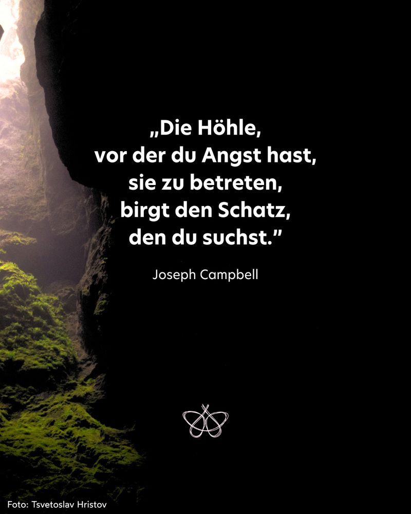 Auf der linken Bildseite ist der EIngang einer Höhle zu sehen, durch den schwacher Sonnenschein eindringt.
In der Bildmitte steht: „Die Höhle, vor der du Angst hast, sie zu betreten, birgt den Schatz, den du suchst.”
Das Zitat stammt von Joseph Campbell.
