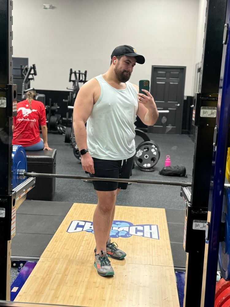 Mirror selfie at a squat rack between sets of rows 