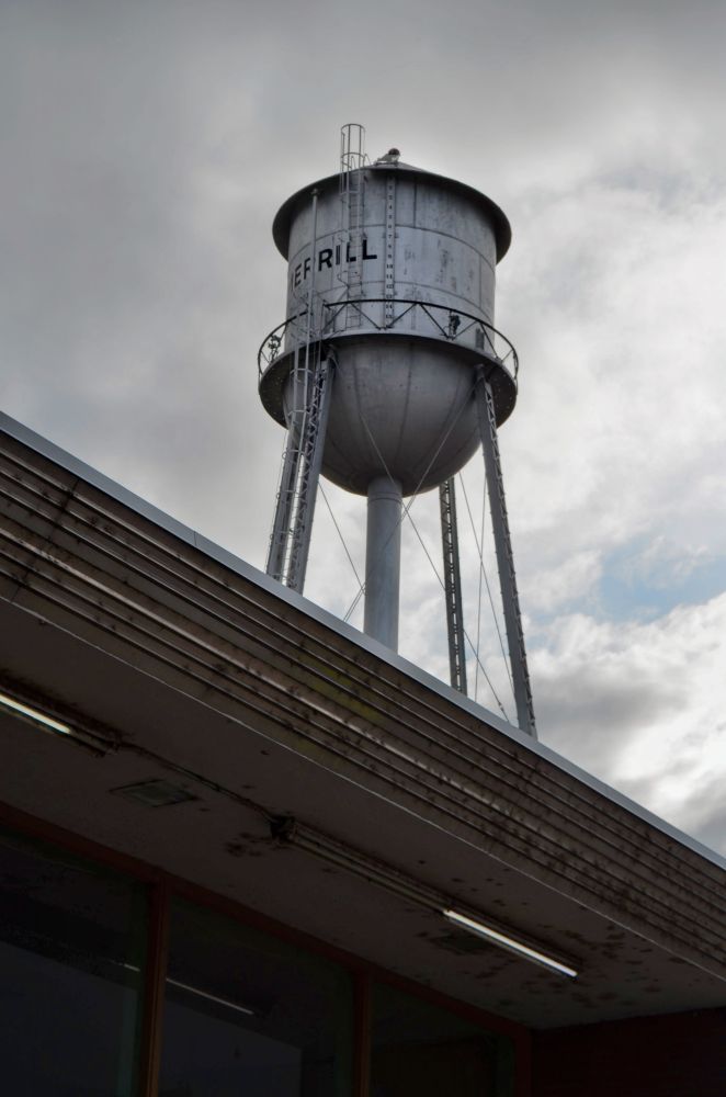 a water tower showing behind the roof of a building.