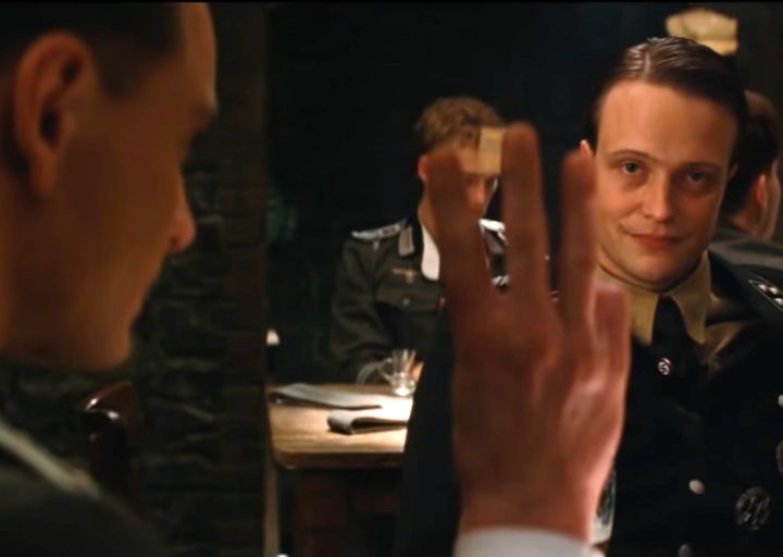 a spy posing as a Nazi holds up his fingers to sign the number three, but he does so like an American instead of like a German, which signals the is a spy