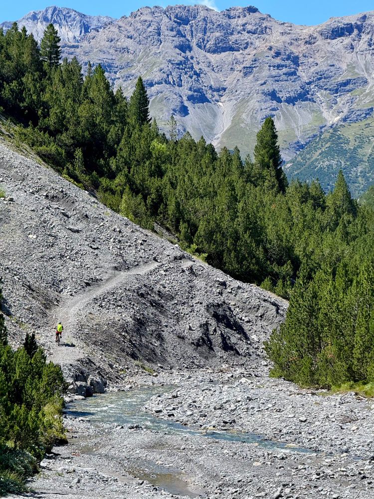 ein biker auf dem schotterweg, daneben der fluss