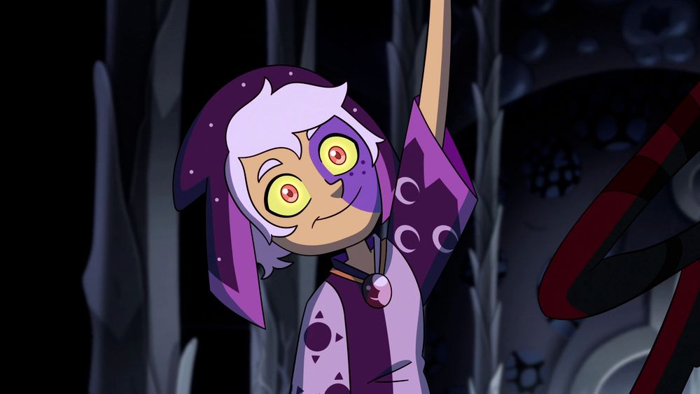 The Collector from Owl House. They have white hair, with a purple flap-hat draped over their head. They're wearing a matching purple and lavender jumper with sun and moon symbols. A purple birth mark covers the left side of their face. Their eyes are wide and crazed, yellow outside and pink irises. They are smiling crazily 