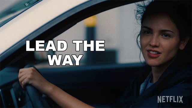 a woman driving a car with the words lead the way written on the screen