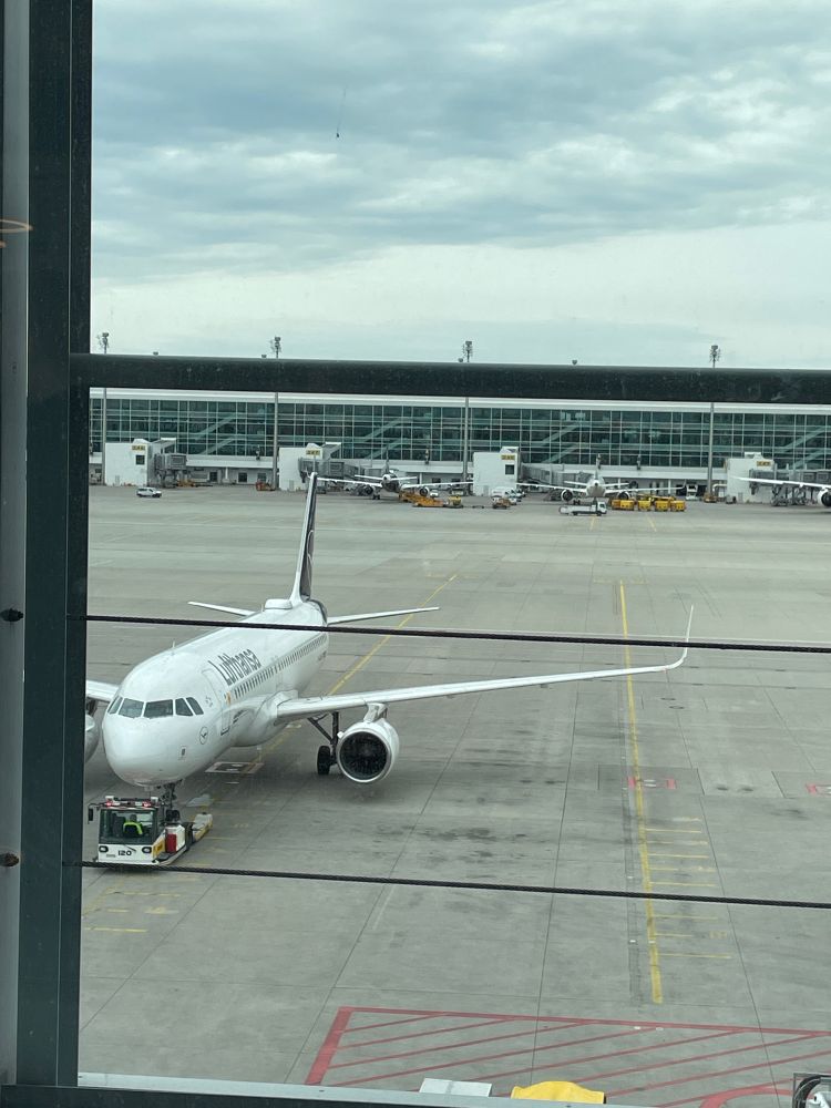 A photo of a plane in a parking bay with a terminal behind it