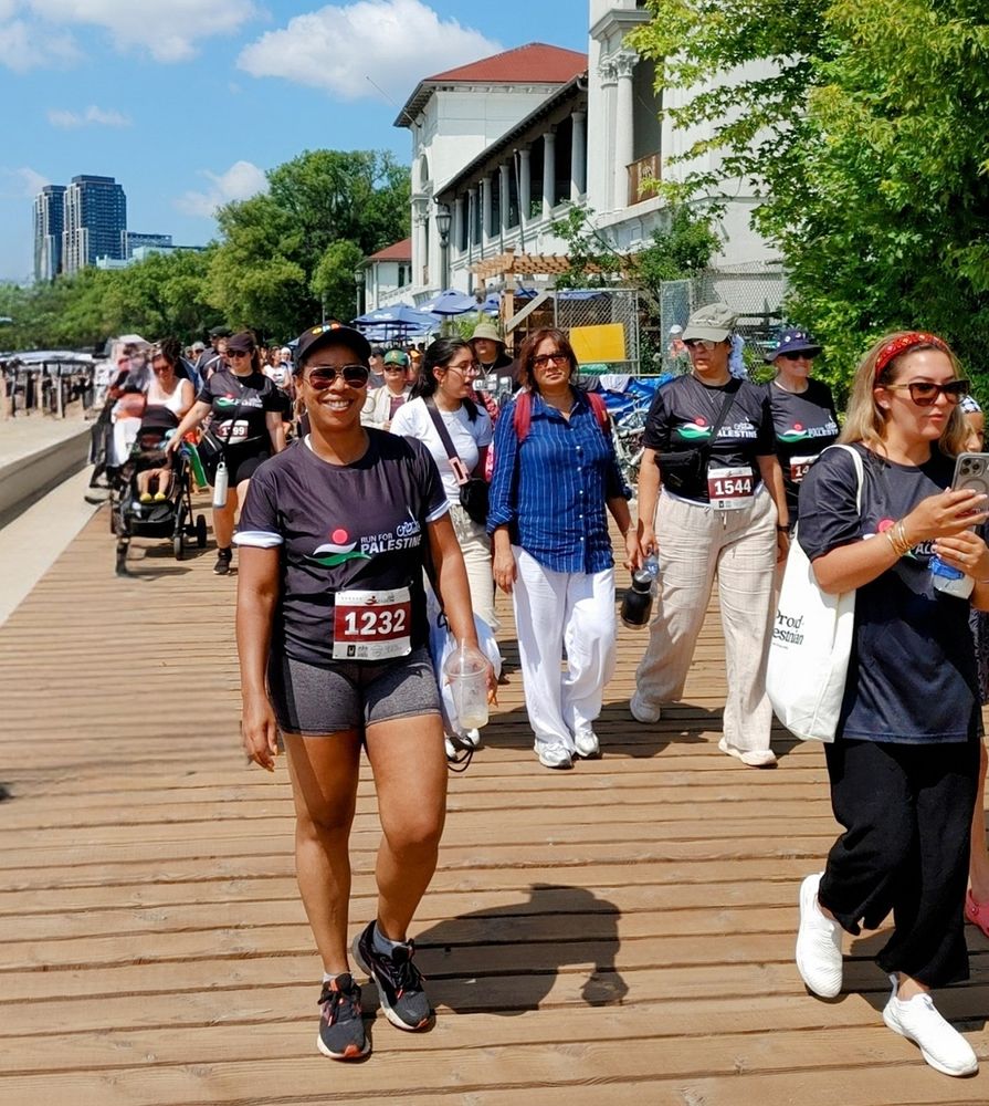 Debbie walking along boardwalk with other walkers in race bibs.