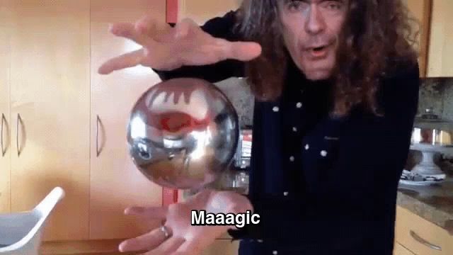 a man with long curly hair is holding a glass ball in his hands and says maaagic