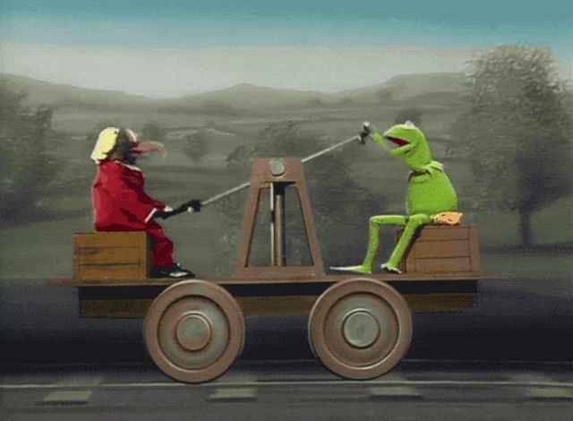 kermit the frog is sitting on a wagon with a clown behind him