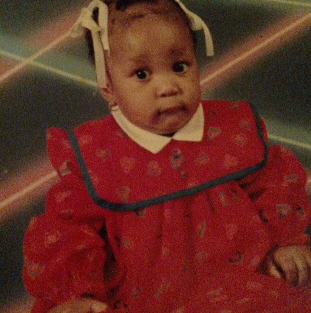 photo of me as a teeny weeny that is absolutely fuckin ridiculous. I'm wearing a red dress with very sharp shoulders for some reason, long poofy sleeves, a white collar, and some kind of black-bordered bib-type shoulder drapery? I'm sorry this is hard to describe but it's absurd looking. I have two white bows in my hair. I do not have nearly enough hair to warrant two white bows--it's patchier than a muhfucka. My eyes are big, my nose is smol, my cheeks are pudgy, my mouth is kinda straight but with my top lip over my bottom lip somehow? My whole expression kinda reads like I know how ridiculous I look. Like I'm thinking 'mother why I have you betrayed me?' Oh and I almost forgot there are neon lasers in the background!