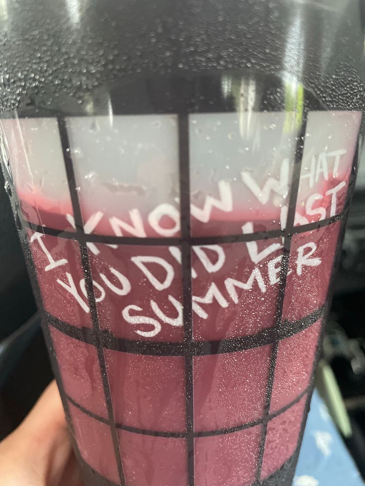 Closeup photo of a plastic cup showing a window with the words “I KNOW WHAT YOU DID LAST SUMMER” written across it. Liquid inside the cup has turned the majority of the window panes dark red, while the top of the cup that’s empty has white panes. 