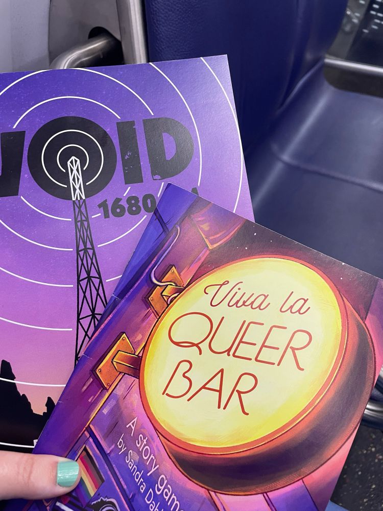 Photo of two softcover books, one for VOID 1680AM and the other held on top of Viva La QUEER BAR.