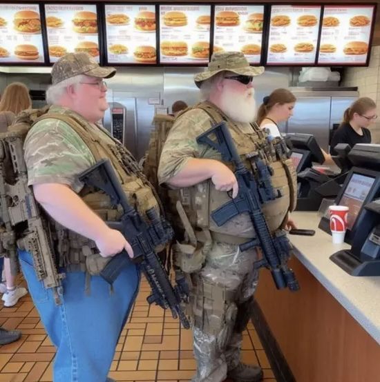 2 large geriatric men hold assault rifles in their right hands, trigger fingers near triggers, while standing in line at a fast food joint. The man on the left cannot see behind him, where he's carelessly positioned yet another assault rifle behind him, inviting gunfire.