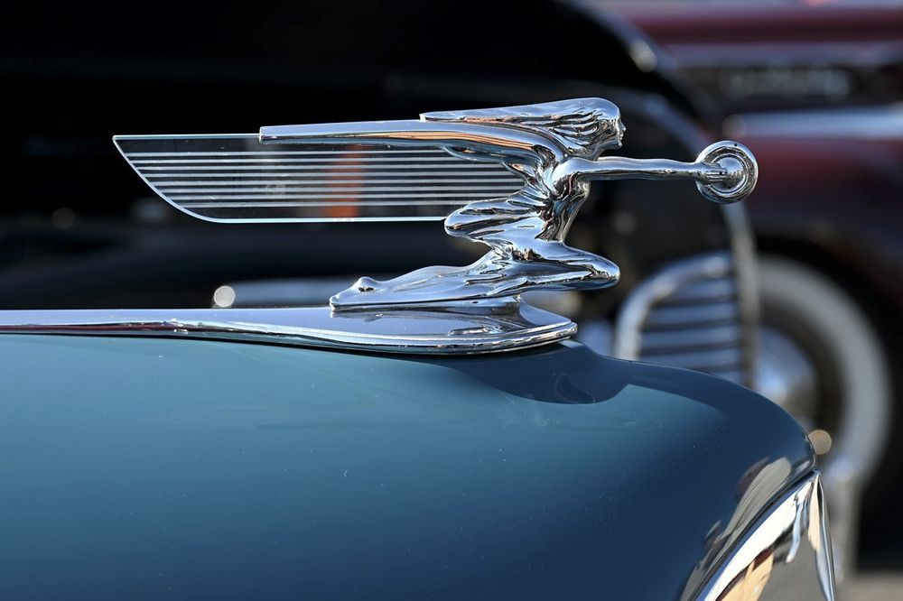 "Goddess of Speed" holding a tire in front of her,
her hair & translucent wing flowing behind her.
Hood ornament on blue Packard.
© TMcDermott 24/07/14
