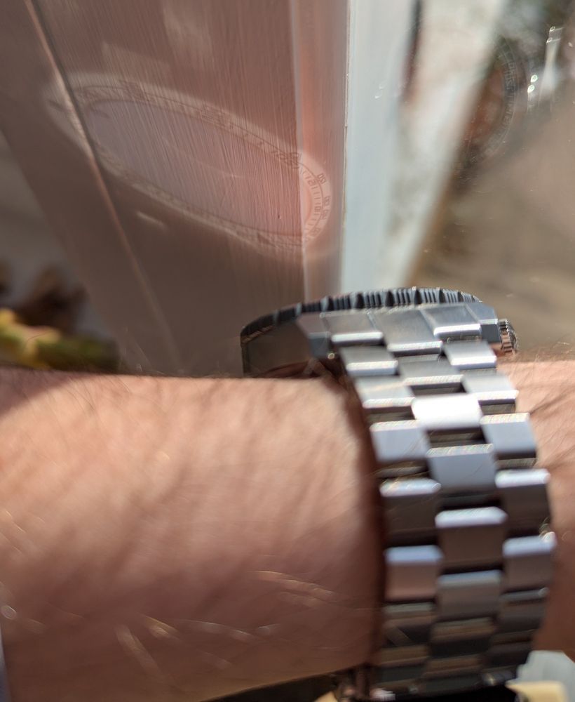 The reflection of the dial of a watch. The reflection has a blue face, white outer ring, with black labels