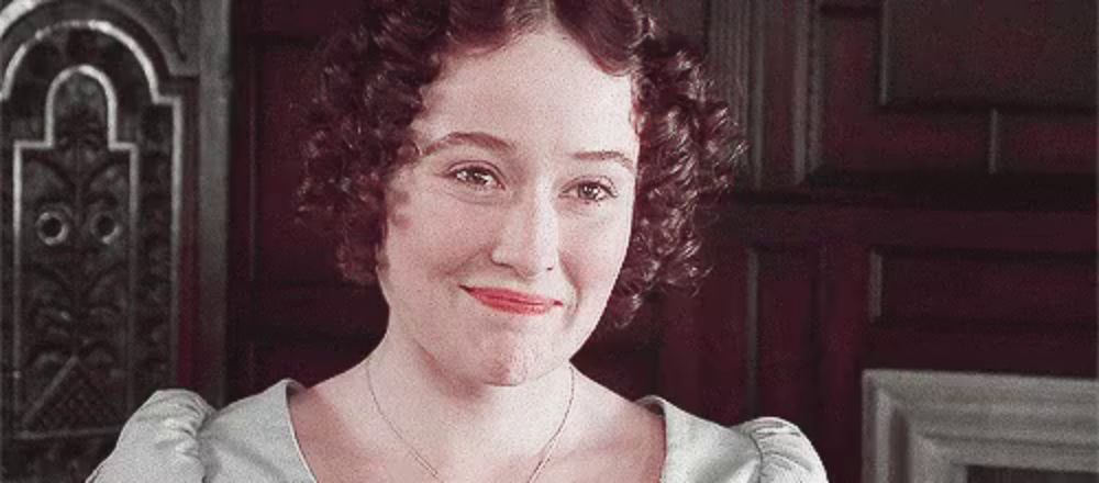 a woman with curly hair is smiling in front of a door .