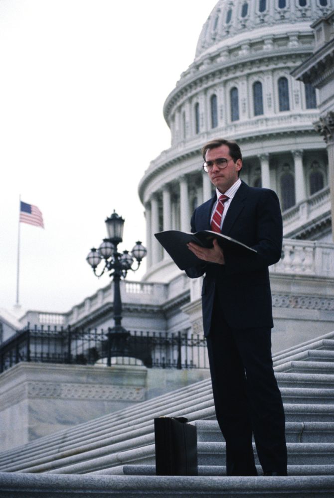 Man in a suit on the steps of the US Capitol.