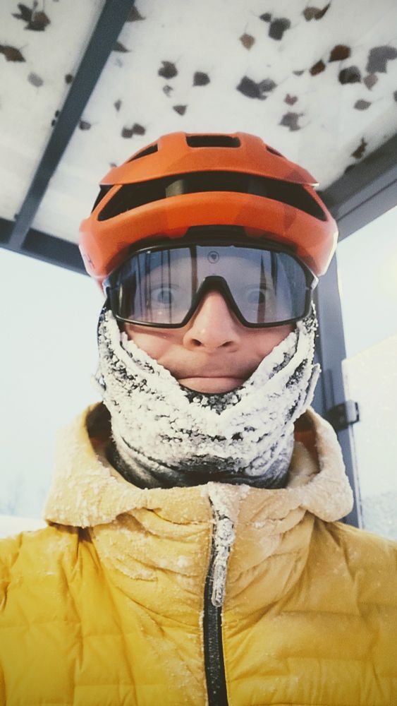 Kuurapartainen pyöräilijä oranssi kypärä päässä.