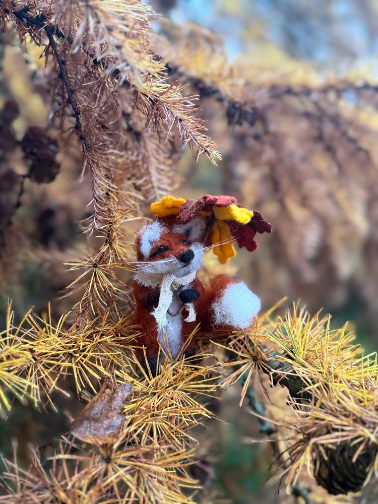Needle felted fox with a felt leaf umbrella on a fir branch 