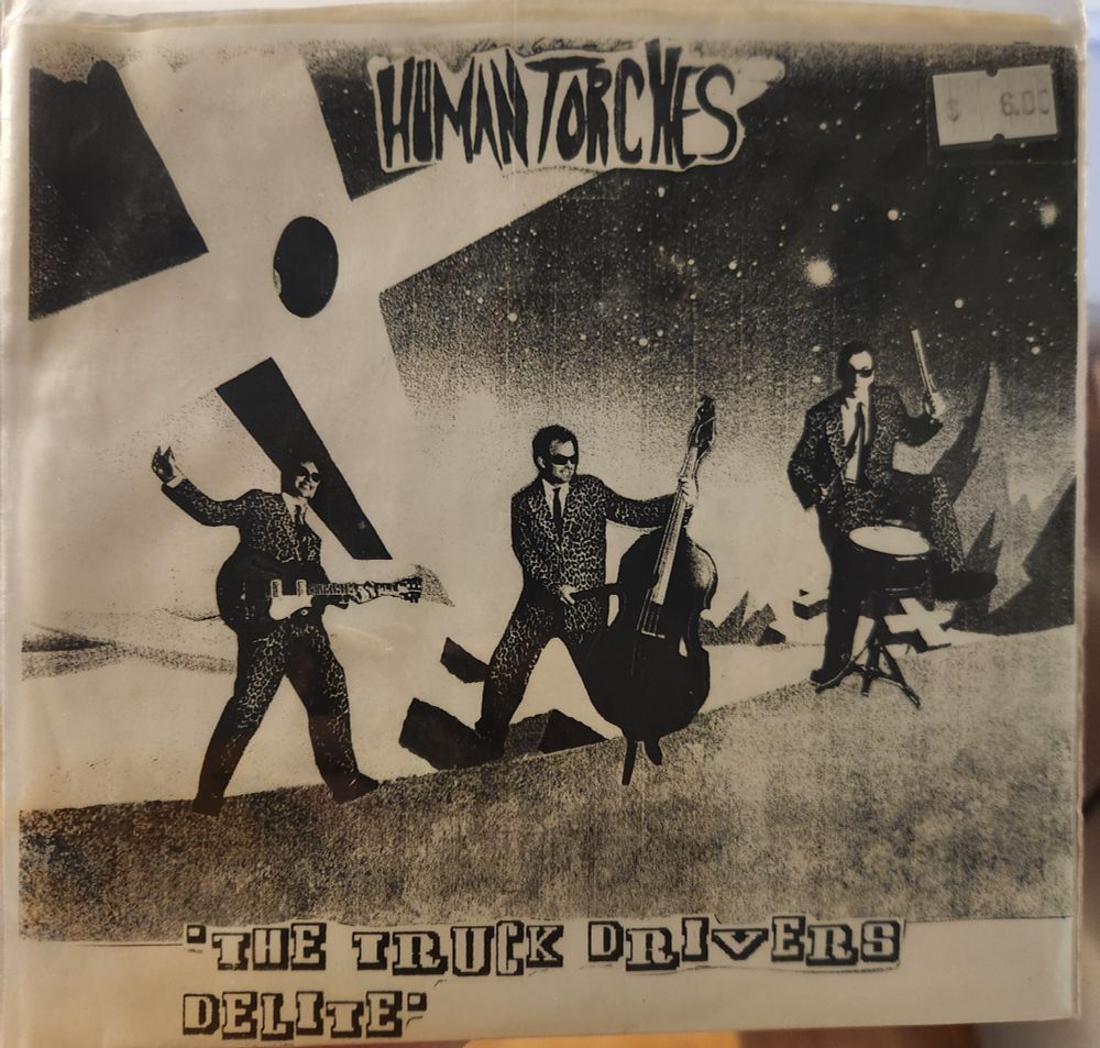 The very photocopied cover of the Epstein Human Torches - The Truck Driver's Delite. It features three men in wacky suits playing instruments on a cliff side.