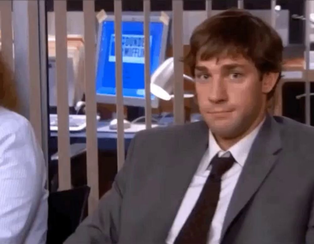 a man in a suit and tie is sitting in front of a computer in an office .