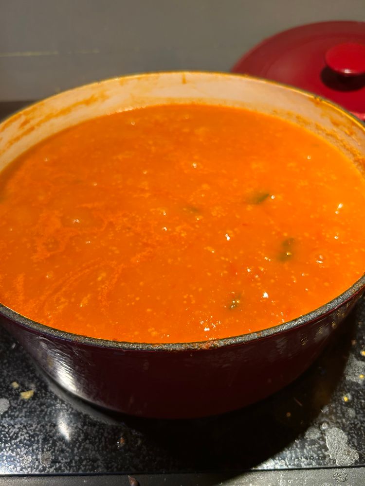 A large pot of simmering tomato sauce on the stop top. 