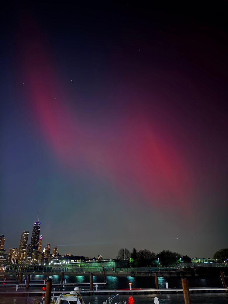 Big red/magenta ribbons of Northern Lights in the sky above Lake Michigan, looking north, northwest from navy pier in Chicago