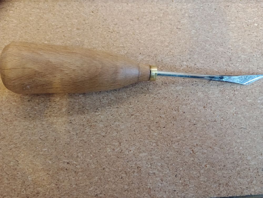 Small knife with wooden handle and cylindrical blade flattened at the end.