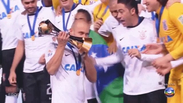 a man holding a trophy in front of a group of players wearing shirts that say caixa