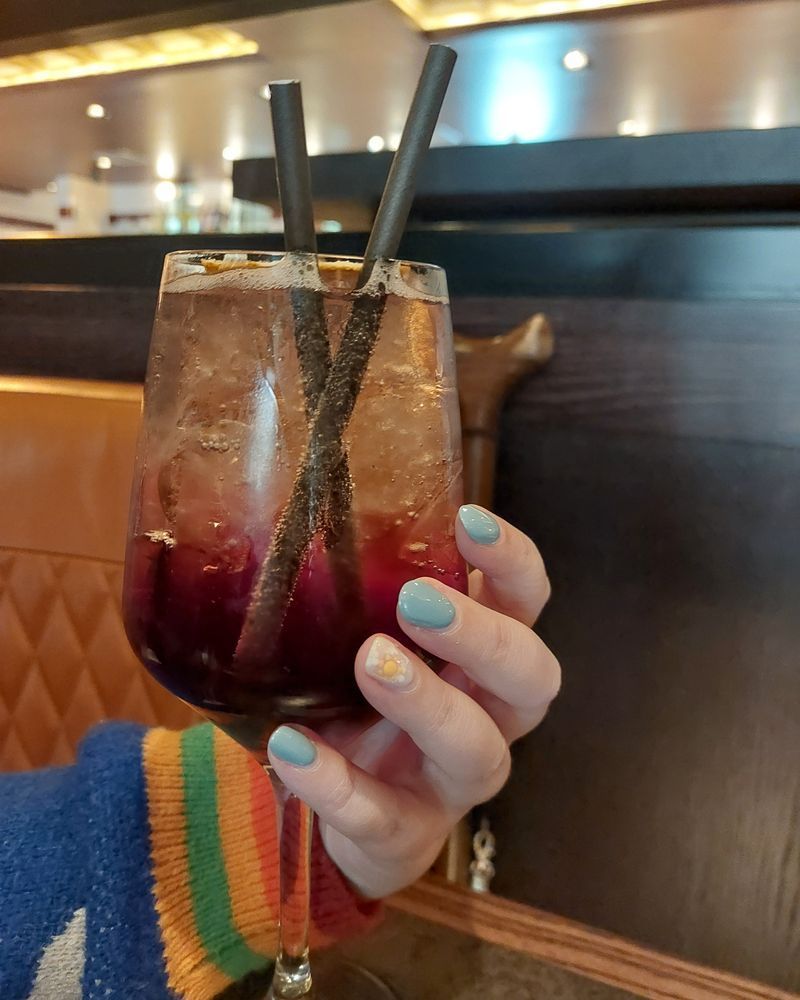 a cocktail in a wine glass. held by miller's hand with cloudy sky nail art
