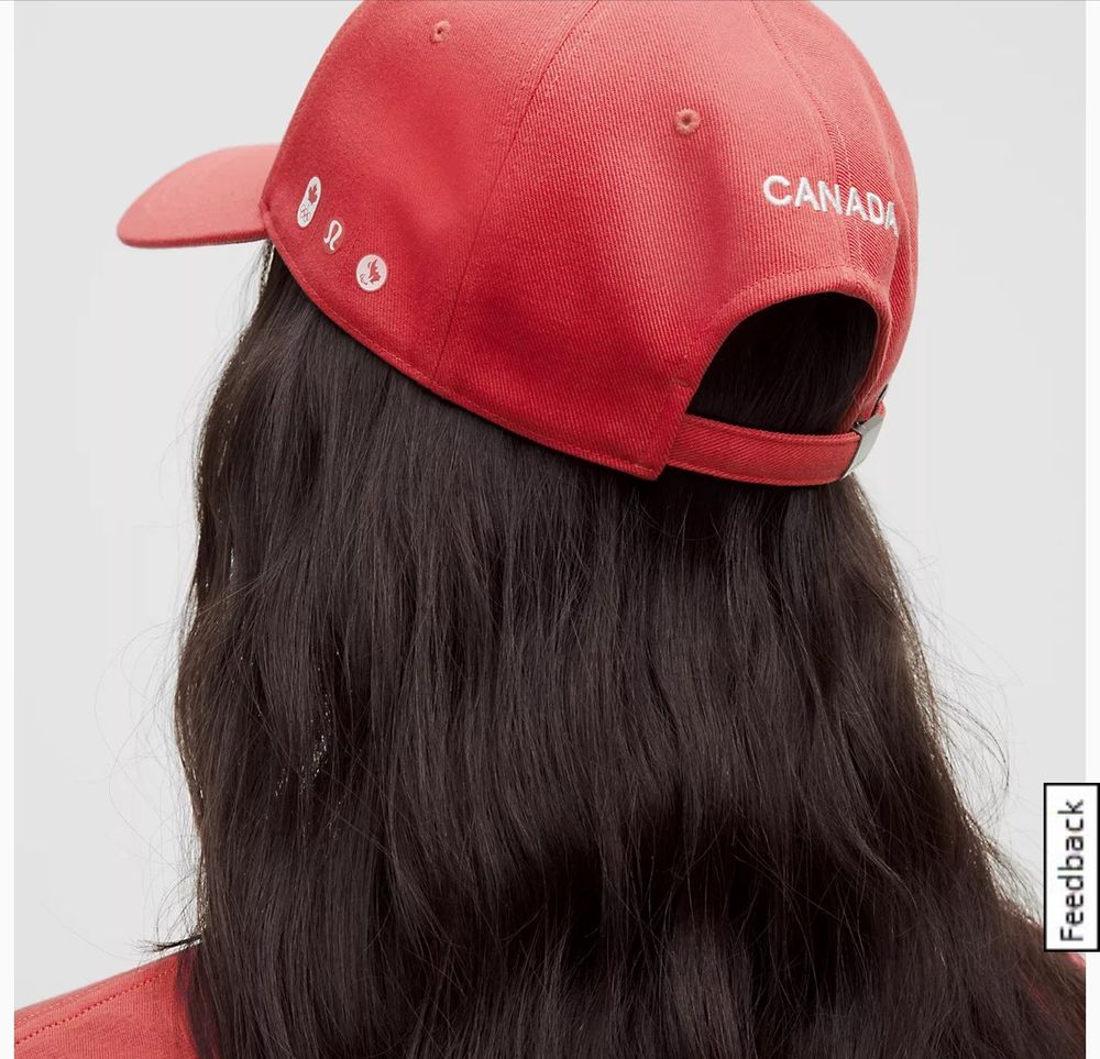 Back of a woman’s head wearing a red ball cap that says CANADA on the back, has Olympics and Special Olympics and Lululemon logos embroidered on the side.