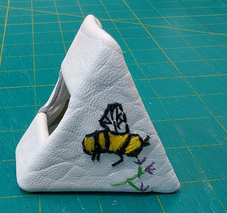 Triangle Shaped Handmade book cover with a black & yellow embroidered bee and a small purple flower