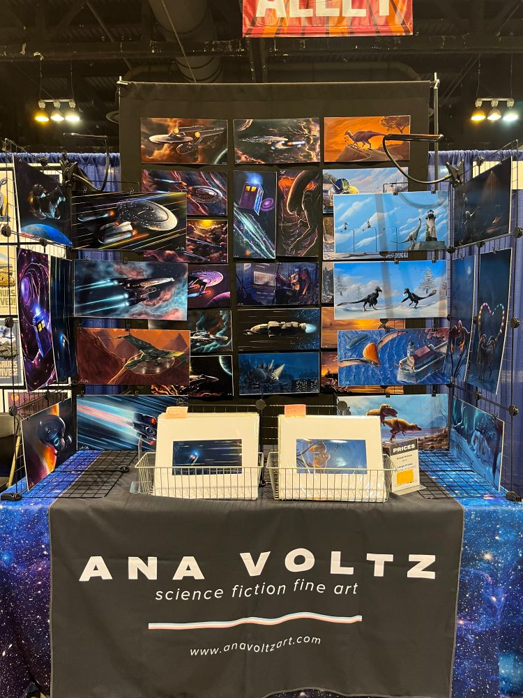 A picture of Ana’s booth, showing a variety of vibrant dinosaur and spaceship art.