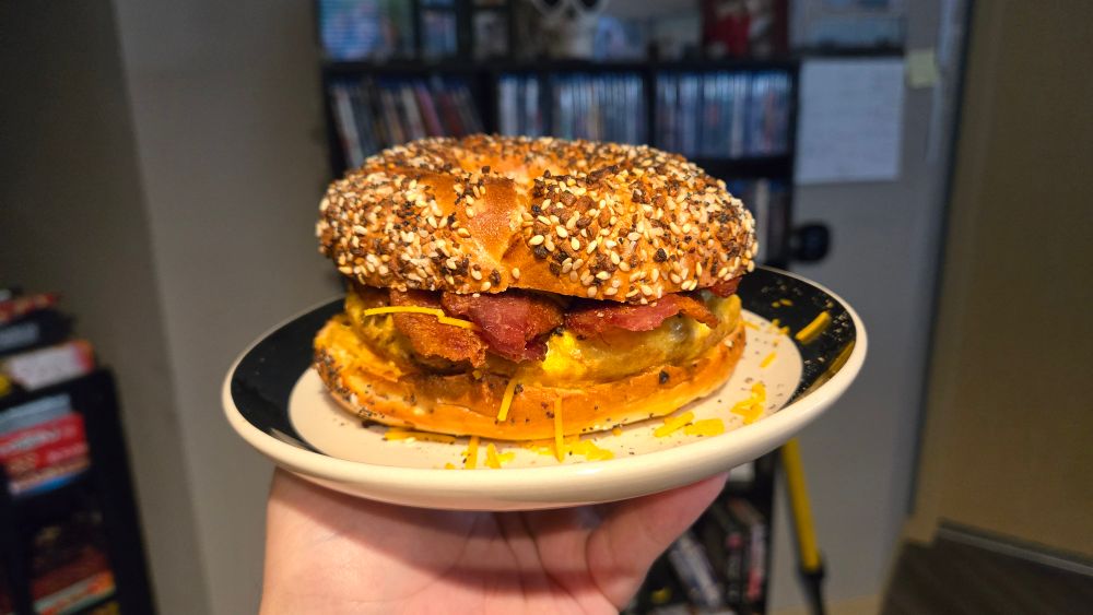 Bacon egg cheese caramelized onions and Sriracha on an everything bagel