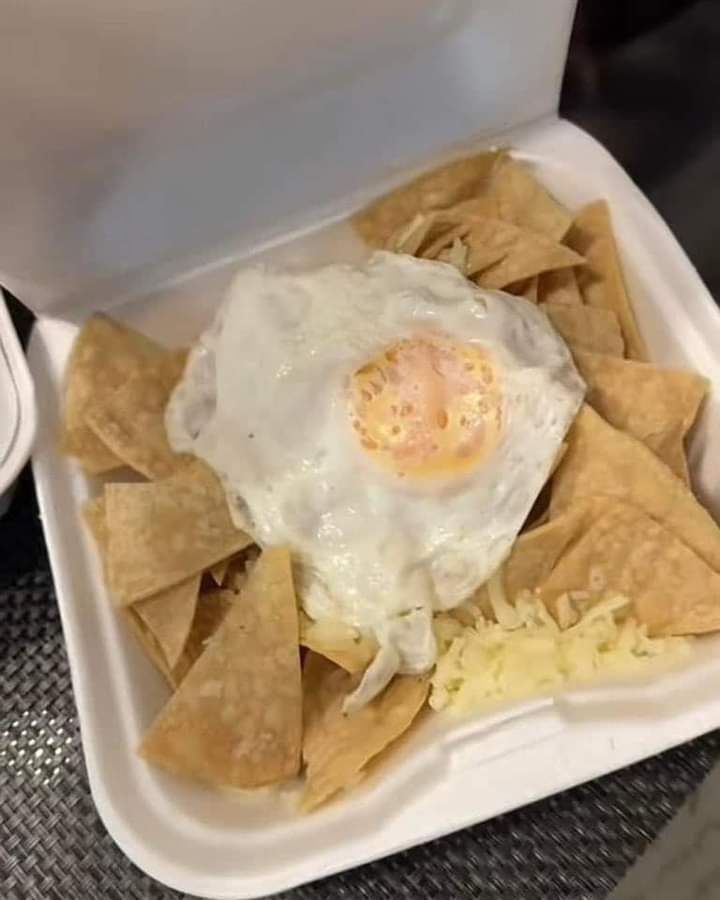 Container of nachoes with an egg on top