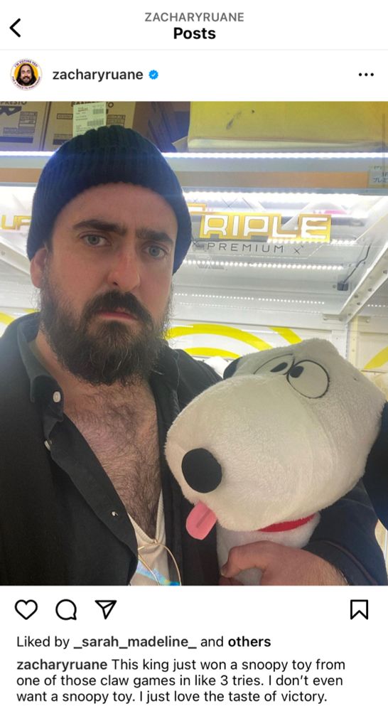 クレーンゲーム機の前で、ニット帽を被ったザッカリーが舌を出してるスヌーピーを抱えてなんとも言えない表情で見つめてくる写真。This king just won a snoopy toy from one of those claw games in like 3 tries. I don't even want a snoopy toy. I just love the taste of victory.