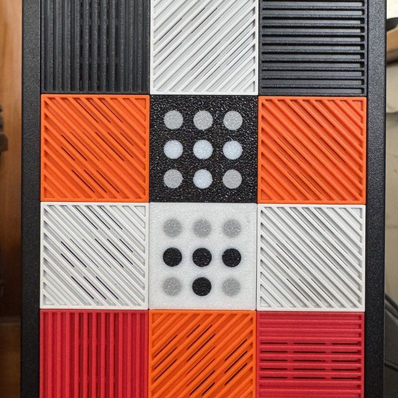 a close-up picture of the front panel of a Framework Desktop computer. The panel has a square matrix of multicolor tiles that can be rearranged per the user's preference. In the center there are two 3D printed tiles with Tailscale logos, one apiece of the light and dark-mode variant, stacked one on top of the other.  