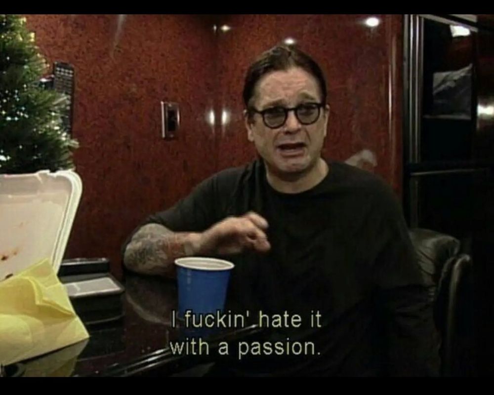 Screenshot aus einer Folge der MTV-Serie "The Osbournes". Ozzy Osbourne sitzt mit Sonnenbrille an einem Tisch, laut Untertiteln sagt er "I fuckin' hate it with a passion."