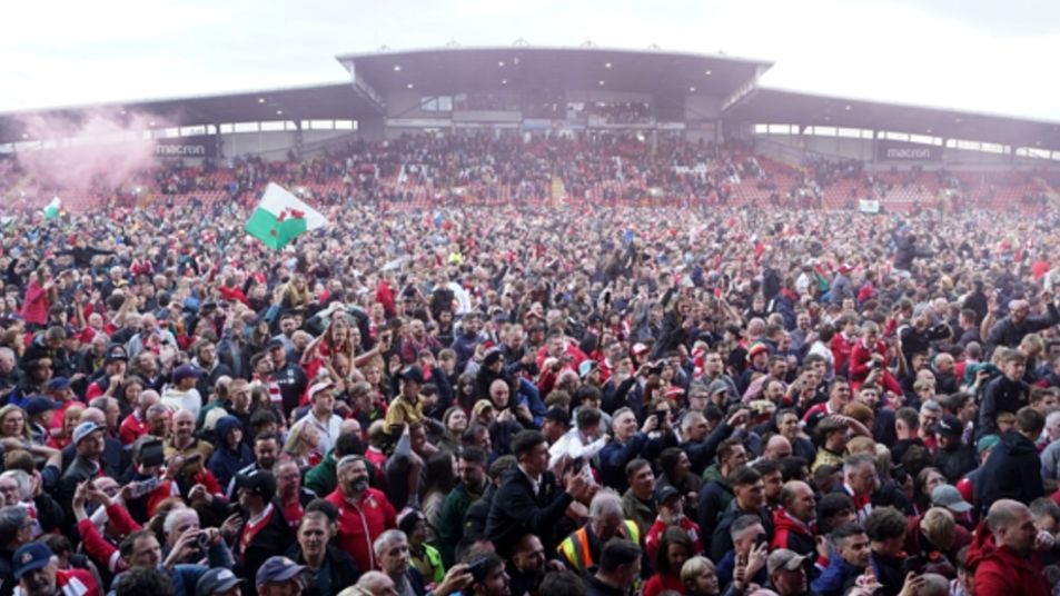 Wrexham fans celebrate on the pitch at the Cae Ras