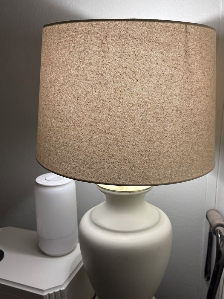 A natural-colored linen lampshade on a cream-colored ceramic "vase" style lamp. 