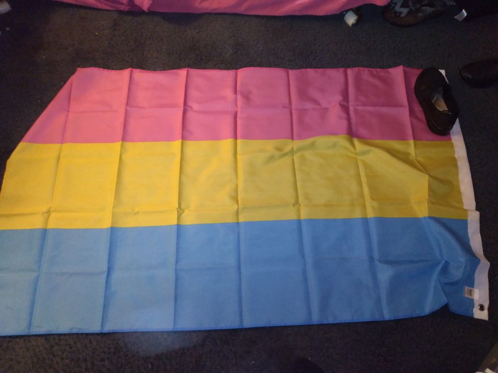 A large pan pride flag, lying on the floor. 