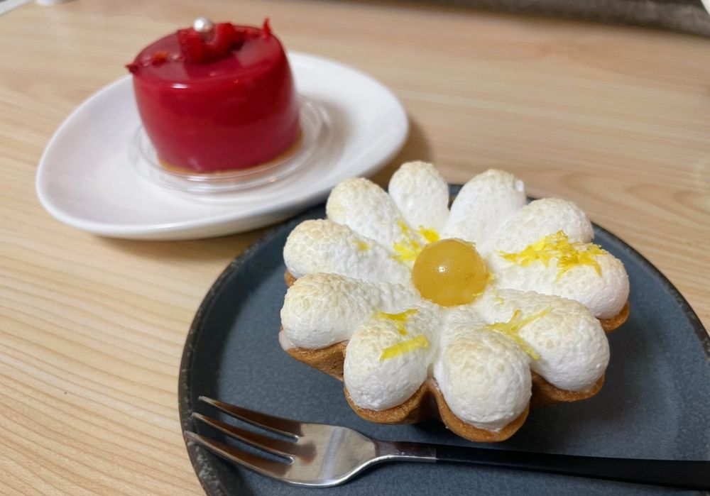 白い花のケーキが手前にあり、奥に赤いケーキがうつっている写真