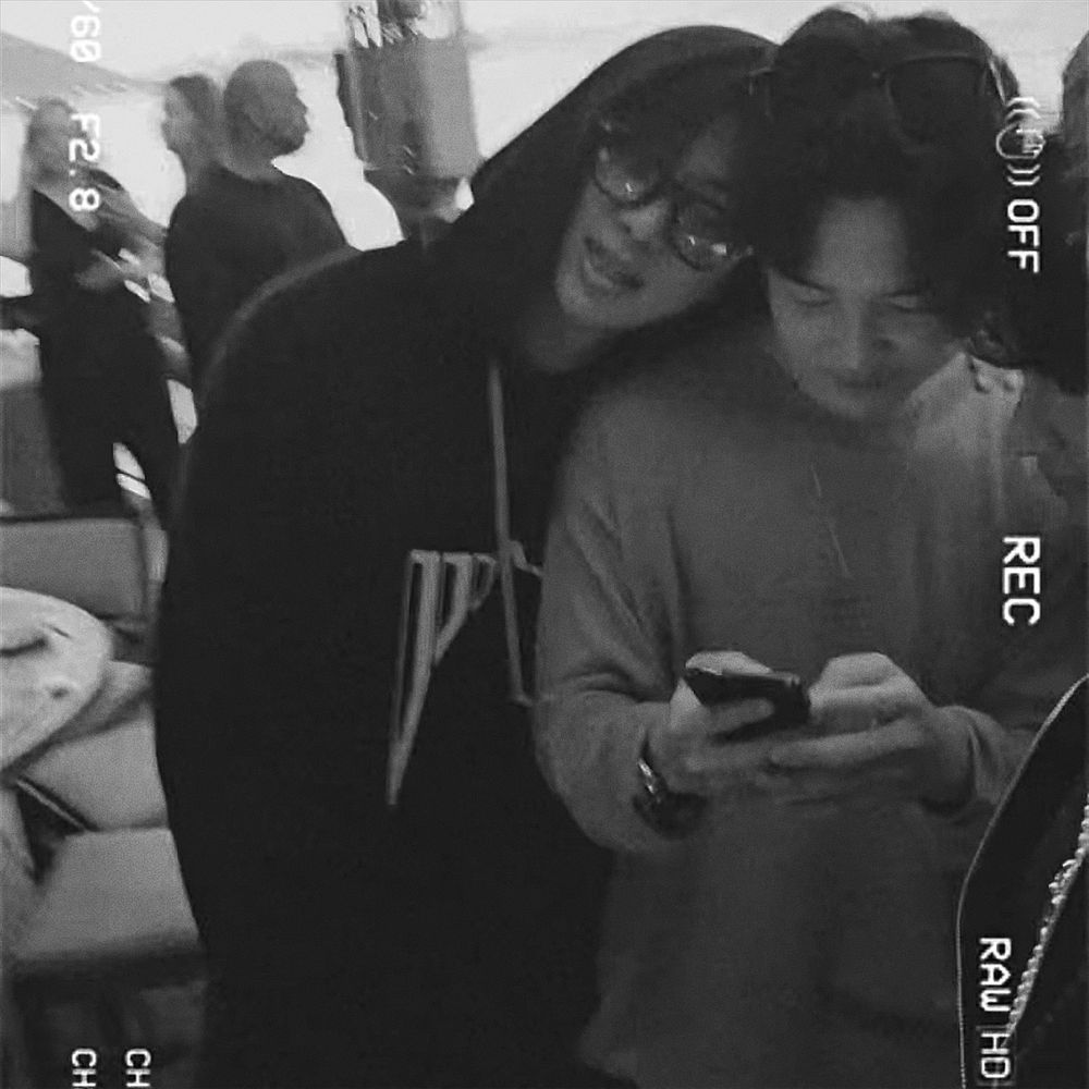 namjoon leaning his head against jimin’s shoulder as they both look down at his phone 