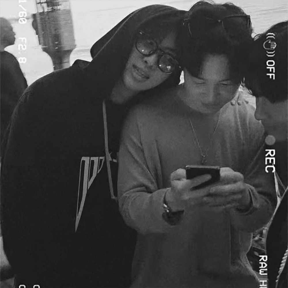 namjoon leaning his head against jimin’s shoulder as jimin looks down at his phone 