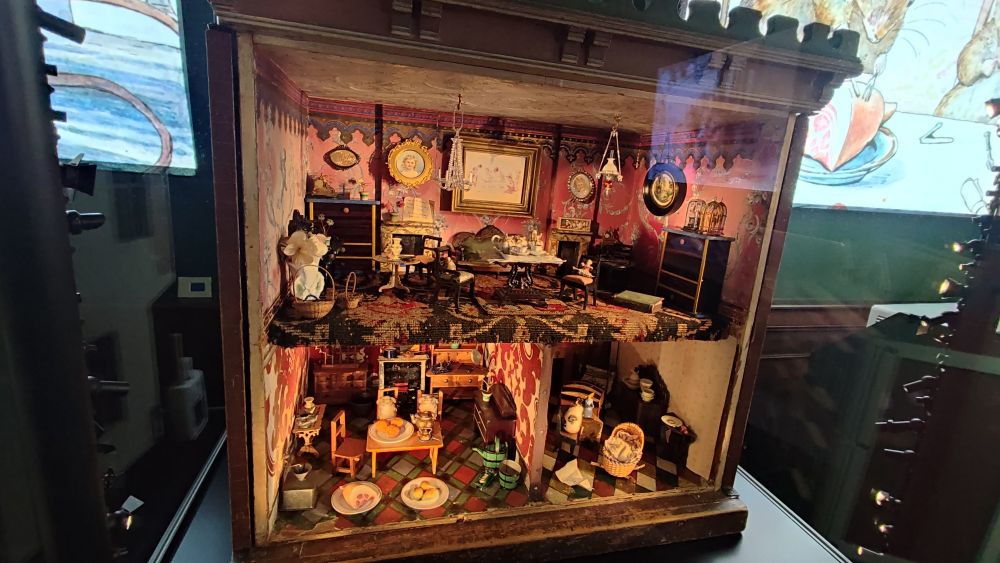 An elaborate, ornate three-room doll's house at Hill Top, Beatrix Potter's house. There are two small mice sitting in the dining room 