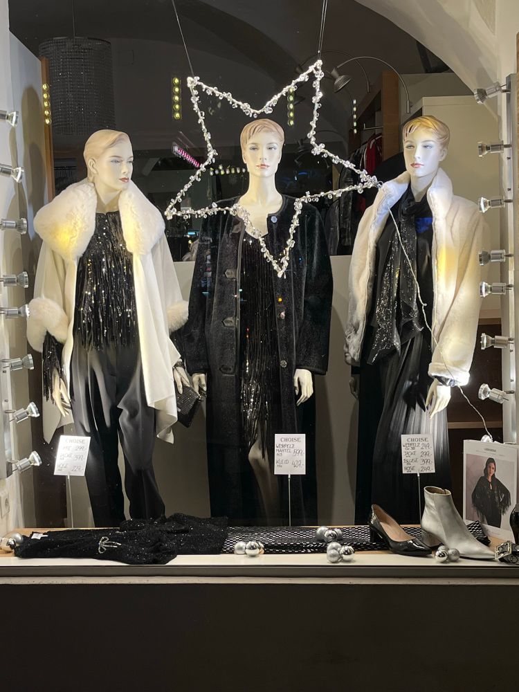 Schaufensterpuppen in schwarzen Kleidern und weißen Mänteln. 