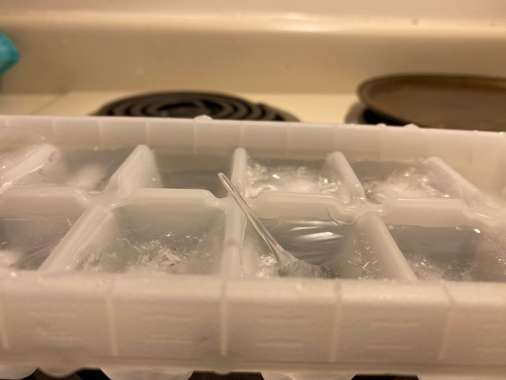 Ice cube tray with spike of ice protruding from the ice that formed as it froze